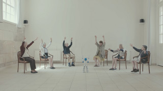 Grupa osób, siedząca w okręgu i naśladująca gesty robota. | A group of people sitting in a circle imitating the robot's gestures.