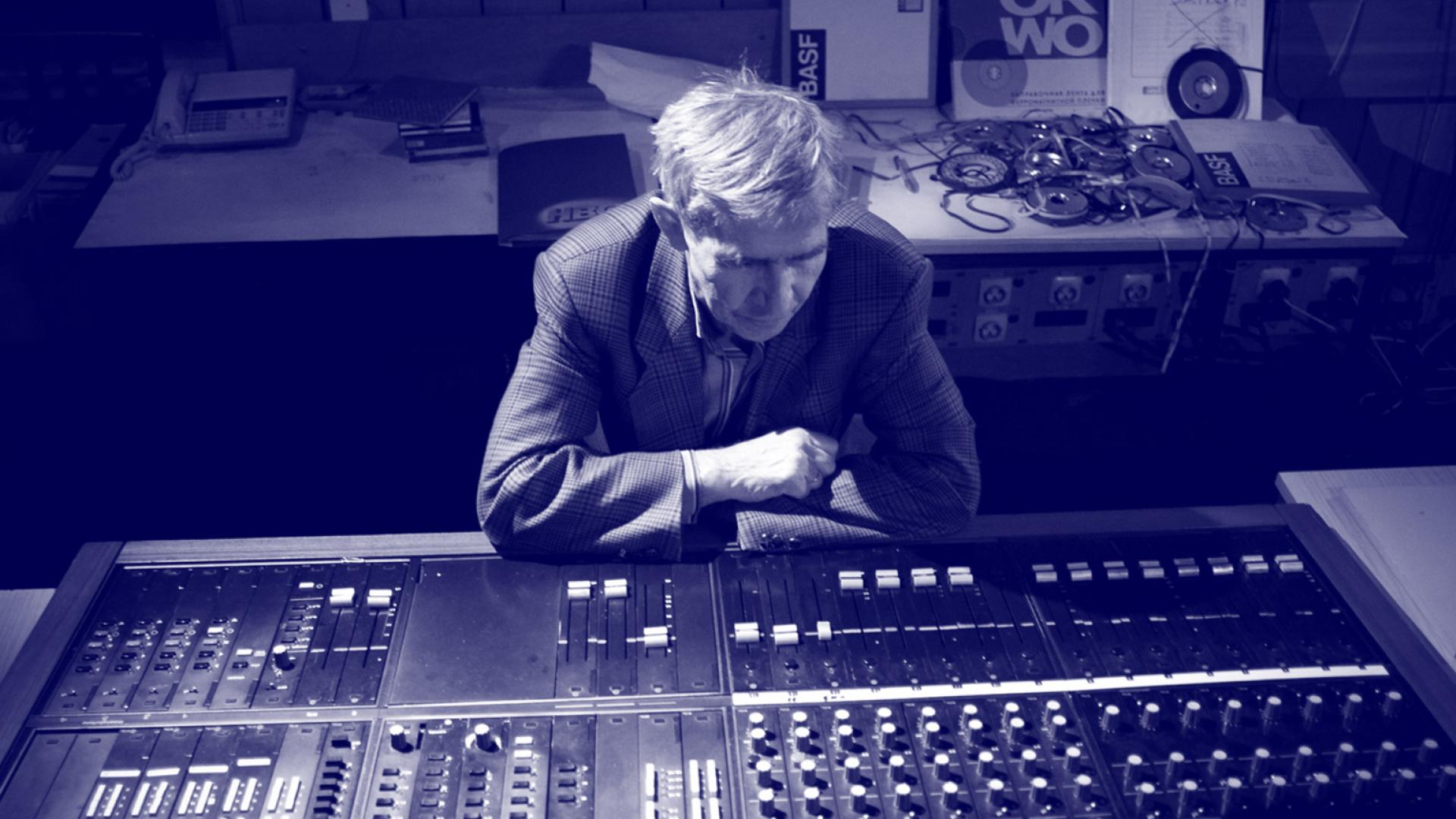 Zdjęcie Eugeniusza Rudnika, siedzącego za konsolą w studiu. | Photo of Eugeniusz Rudnik sitting behind the console in the studio.