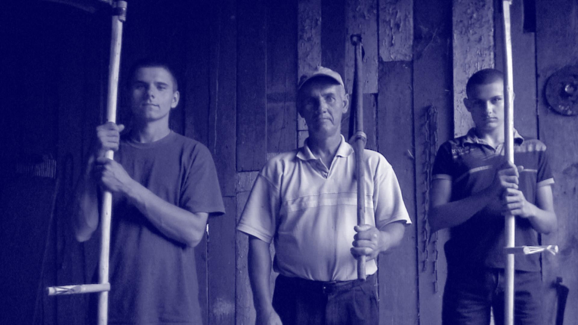 Portret kosynierów: ojciec i dwóch synów z kosami w stodole. | Portrait of blackbirds: father and two sons with scythes in the barn.