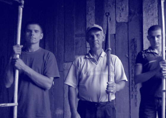 Portret kosynierów: ojciec i dwóch synów z kosami w stodole. | Portrait of blackbirds: father and two sons with scythes in the barn.