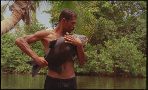 Zdjęcie przedstawia rybaka obejmującego złowioną rybę. | The photo shows a fisherman hugging a caught fish.