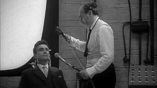 Zdjęcie dwóch bohaterów filmu z mikrofonami. | A photo of two movie characters with microphones.