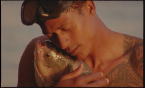 Zdjęcie przedstawia rybaka obejmującego złowioną rybę. | The photo shows a fisherman hugging a caught fish.