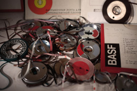 Zdjęcie rozrzuconych taśm z zapisanym dźwiękiem na stole. | Photo of scattered tapes with sound written on the table.