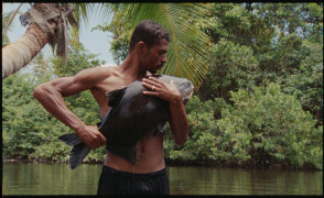 Zdjęcie przedstawia rybaka obejmującego złowioną rybę. | The photo shows a fisherman hugging a caught fish.